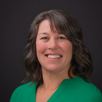 A head shot of Joel Willet, she is wearing a kelly green blouse and has fair skin, blue eyes and dark brown hair.