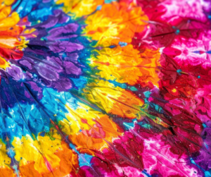 A tie dyed fabric starting with bright orange in the corner moving to purple, blue, green, yellow, orange and finishing with pink in honour of World Autism Day's theme of Celebrate the Specturm.