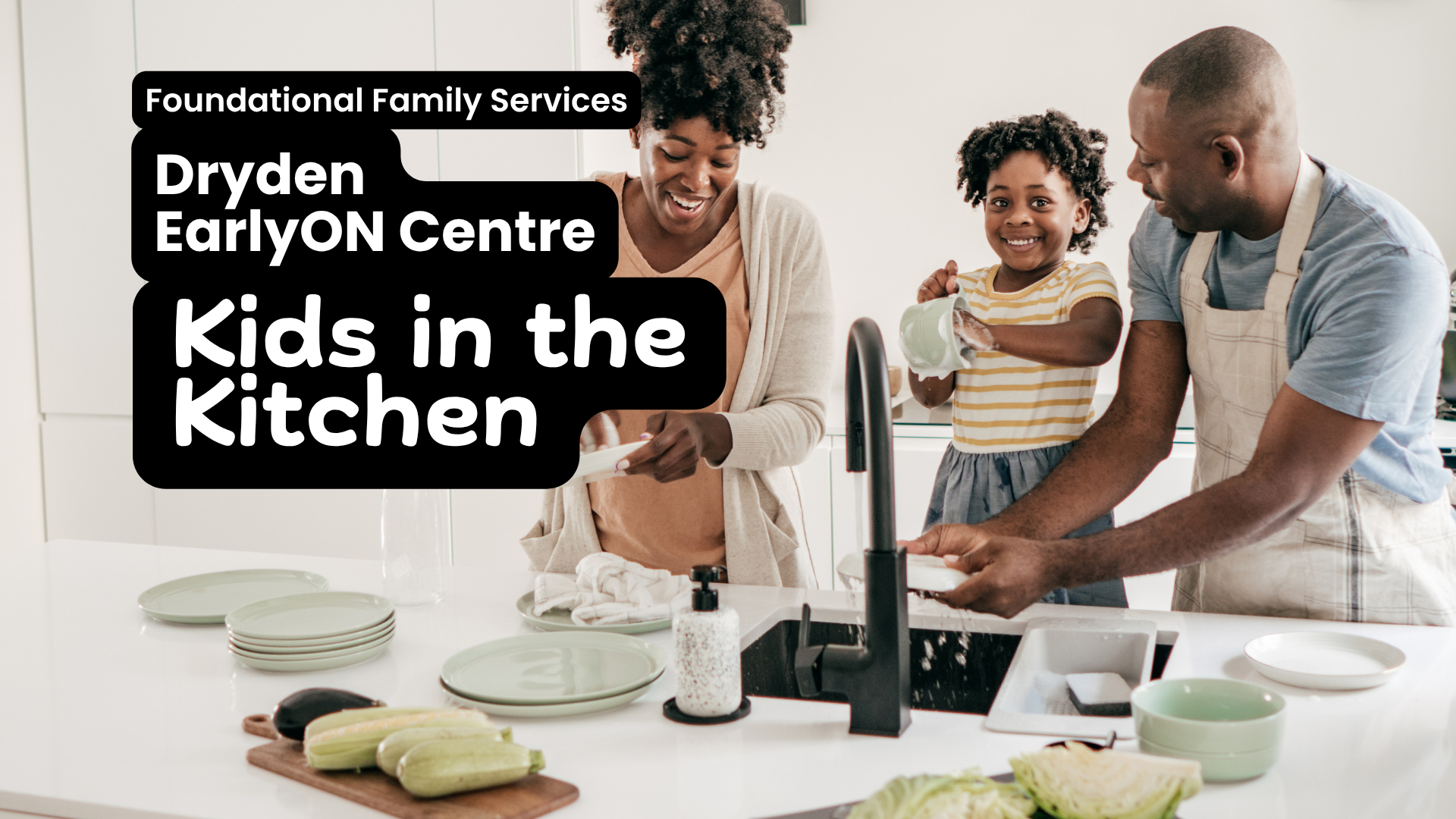 In white text overtop of a black box Foundational Family Services, Dryden EarlyON Centre, Kids in the Kitchen. The image behind the text is a black family having fun cooking in the kitchen together. A young child stands between a woman and man. The man is washing his hands, while the child holds up a pitcher and the woman is dries a plate.