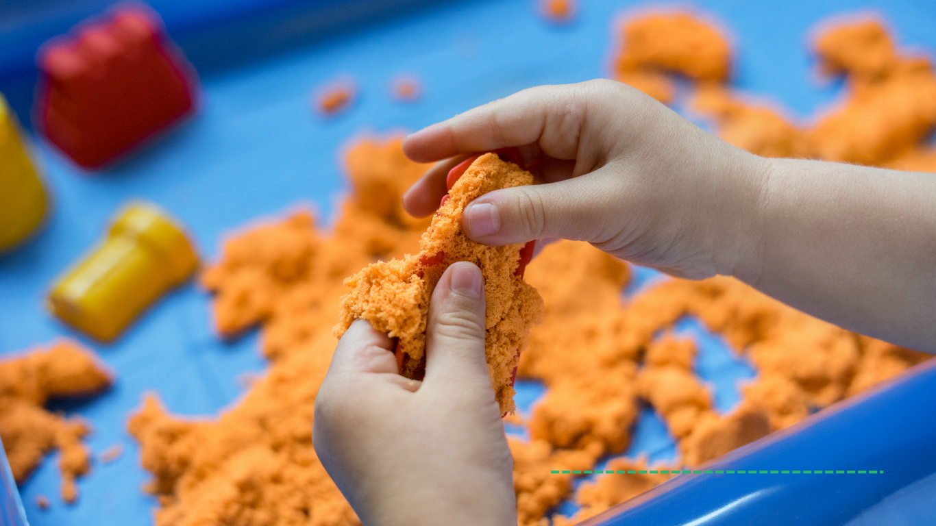 Graphic All Things Sensory- child is playing with an orange squishy material